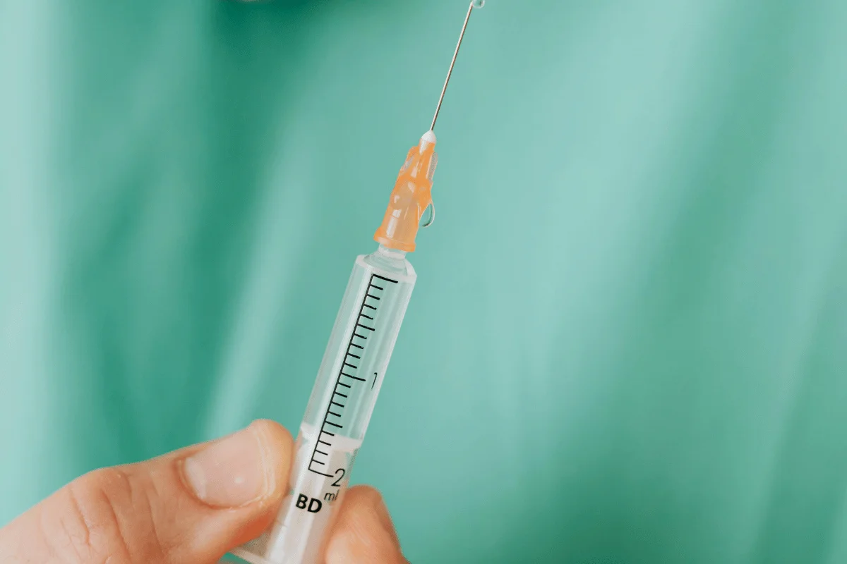 A person holding an injection in their hand.