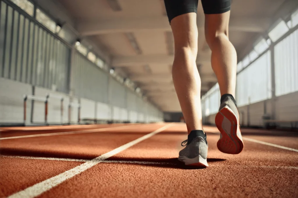 Close-up of an athlete's legs running on a track, focus on running shoes.