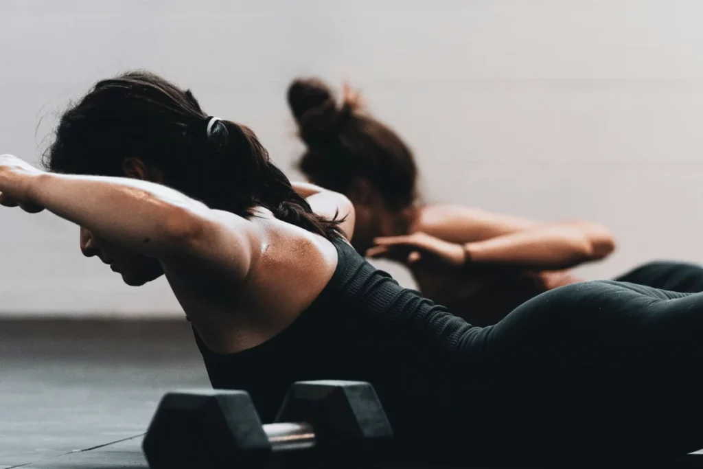 Two women performing floor exercises during a workout session.