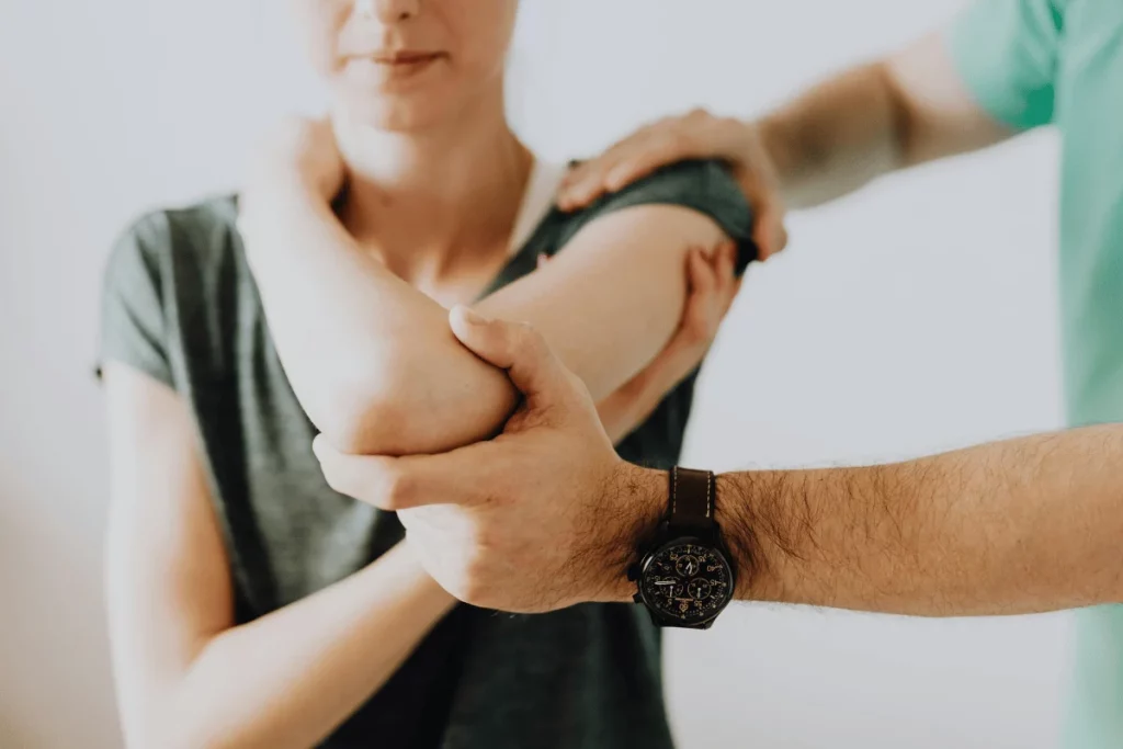 A person examining another's arm, focusing on the elbow joint.