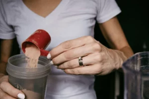 Close-up of a person scooping protein powder into a shaker for a post-workout shake.