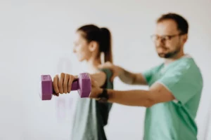 Two people exercising with purple dumbbells in focus.