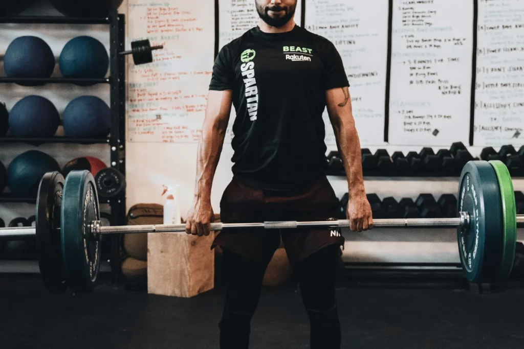 Man performing a deadlift in a gym with weight plates.