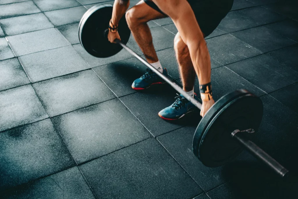 Athlete performing a barbell deadlift on a gym floor, showcasing strength training and proper lifting form.