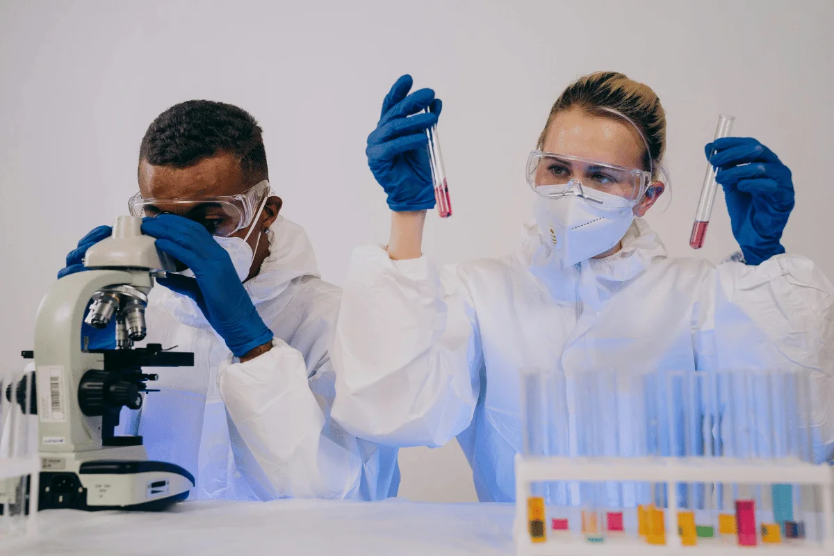 Laboratory technicians in hazmat suits conducting tests with blood samples.