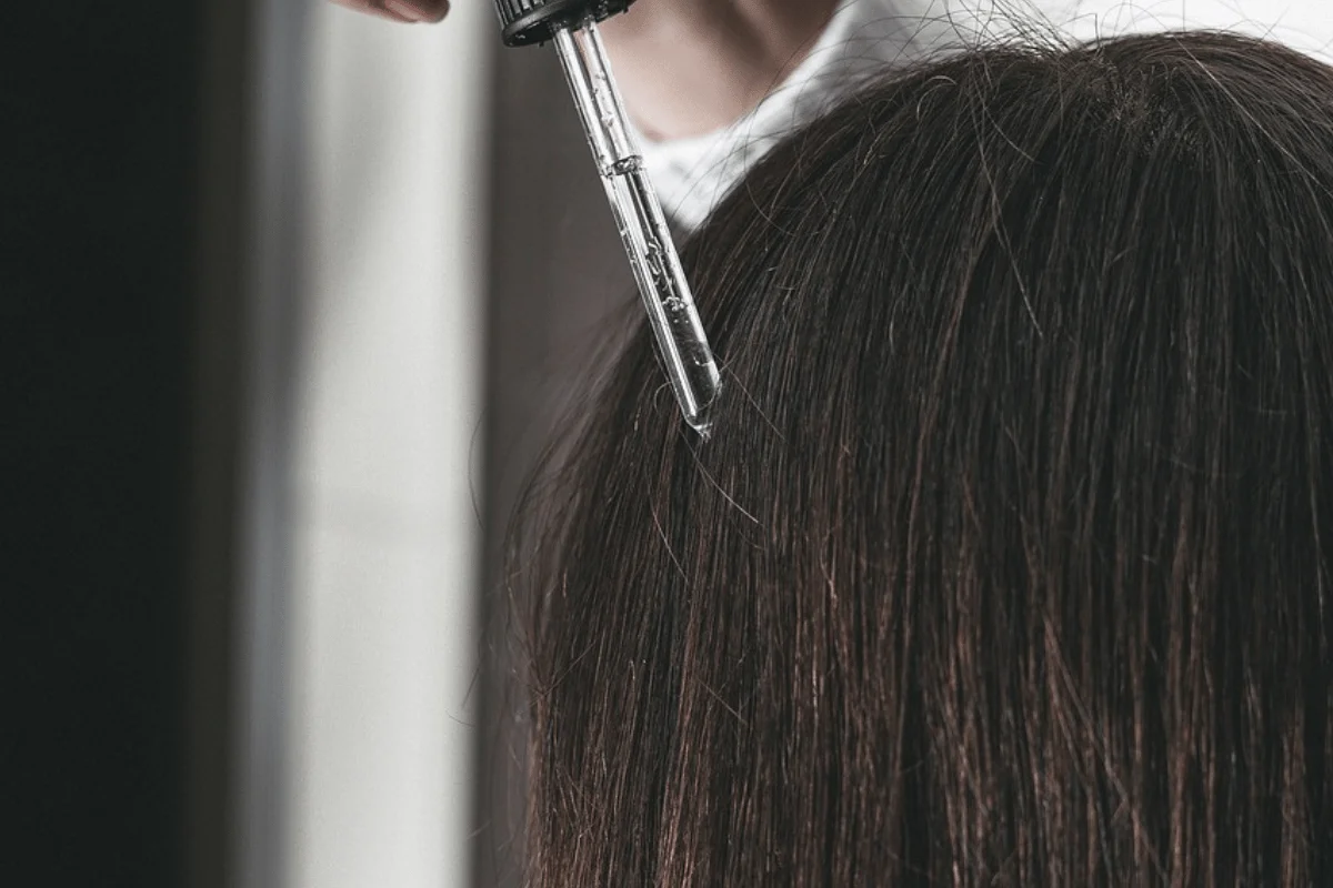 Syringe being injected into the scalp of a person with brown hair.