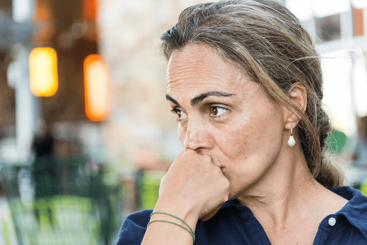 Pensive woman with her hand on her chin, looking away.