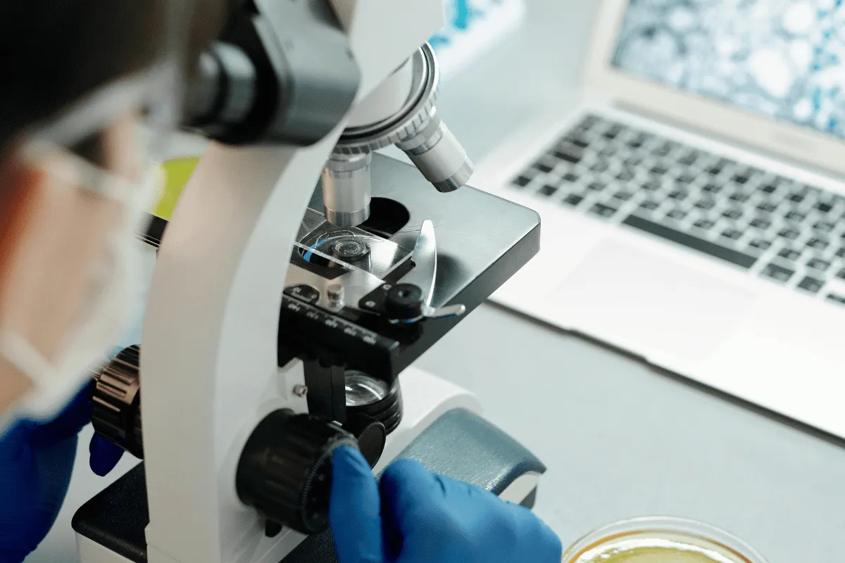 Lab technician examining a sample under a microscope.