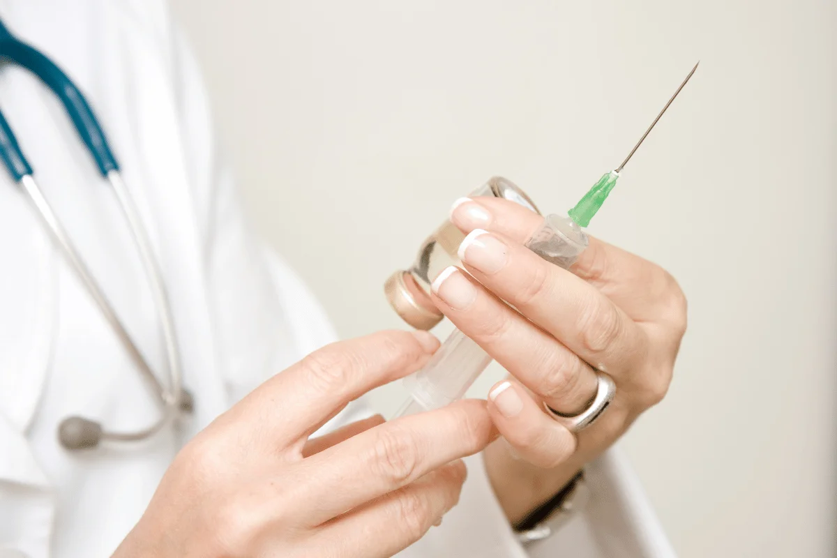 Healthcare professional preparing a syringe with a clear liquid.