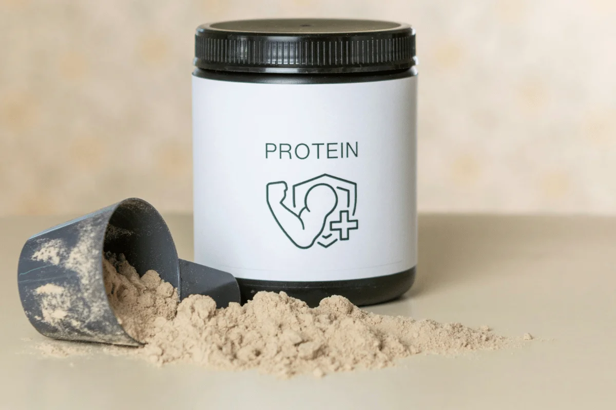 Protein powder spilled from scoop next to a jar of protein supplement.