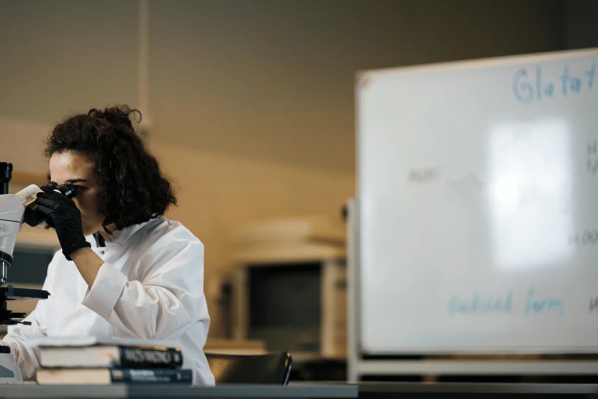 Female lab technician using a microscope for scientific research.