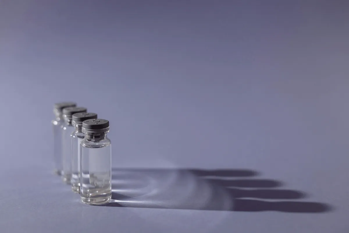 Row of glass vials casting shadows on a gray background.