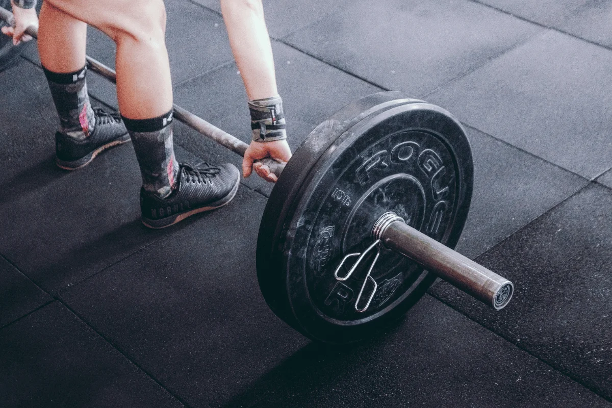 Person preparing to lift a barbell loaded with weights in a gym.