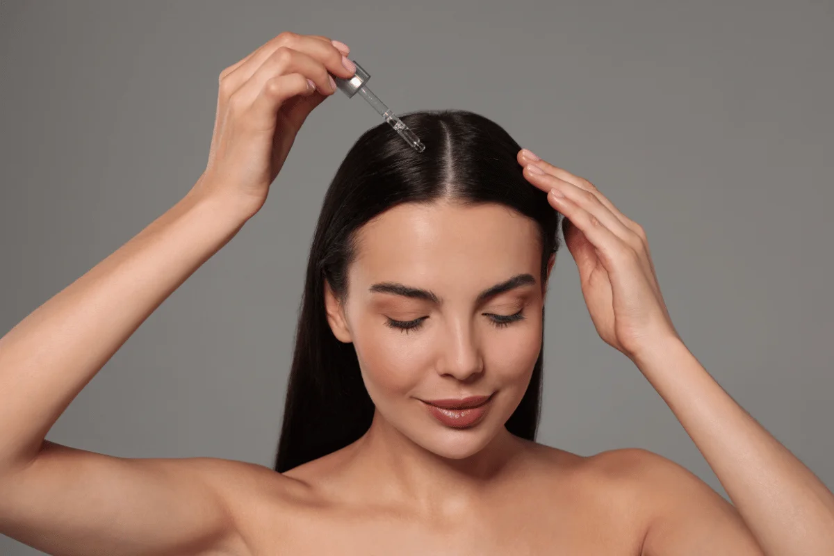 A person is using a dropper in her hair.