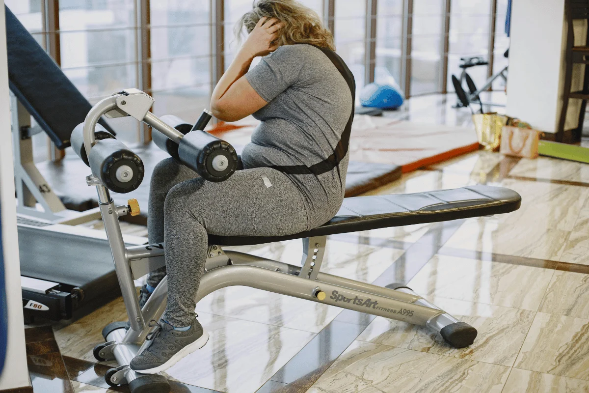 Woman in gray activewear using gym equipment for a core workout.