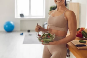 Fit woman holding a fresh salad in workout attire, embracing a healthy lifestyle.