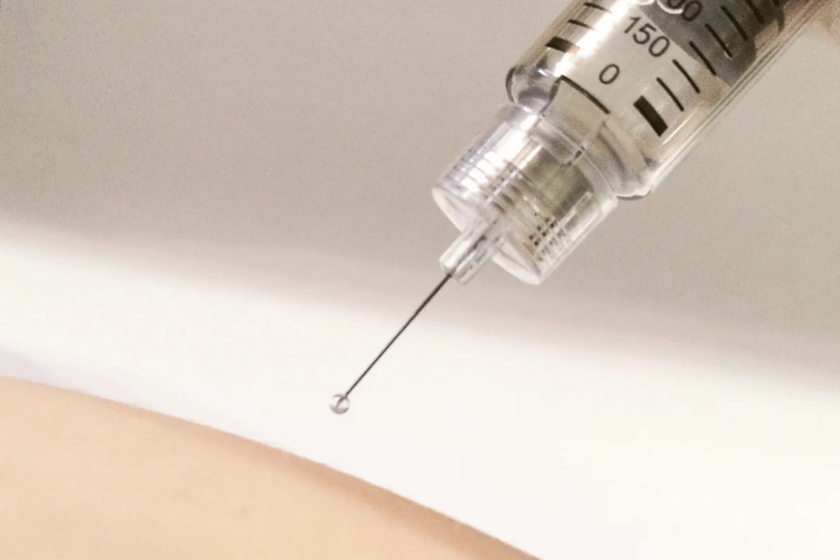 Sterile syringe with a visible droplet, ready for medical or cosmetic use.