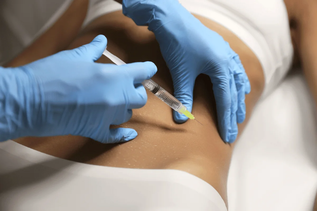 Healthcare professional administering an abdominal injection wearing blue gloves.