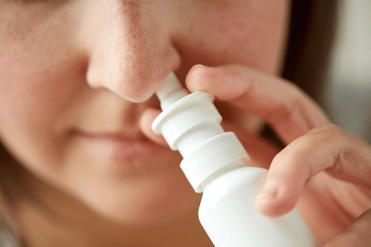 Close-up of a person using a nasal spray for health and wellness.