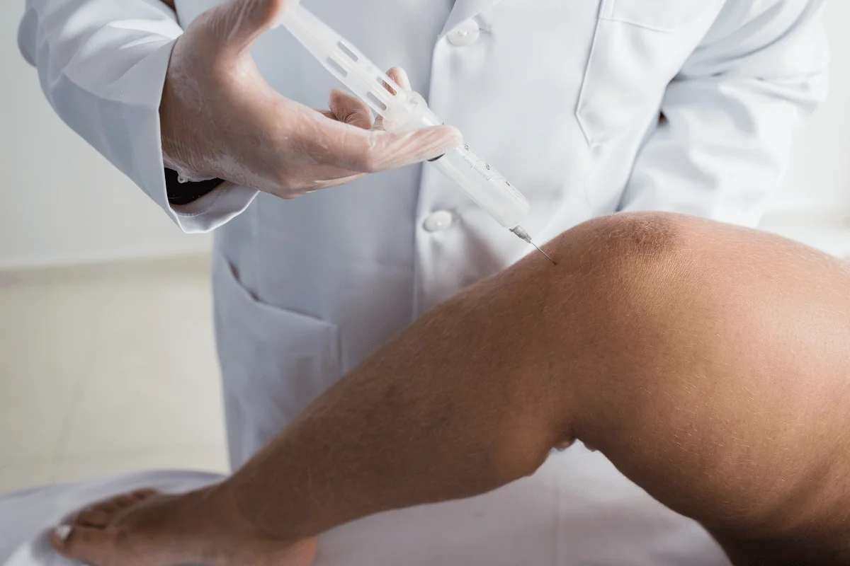 Doctor administering an injection into a patient’s knee for medical treatment.