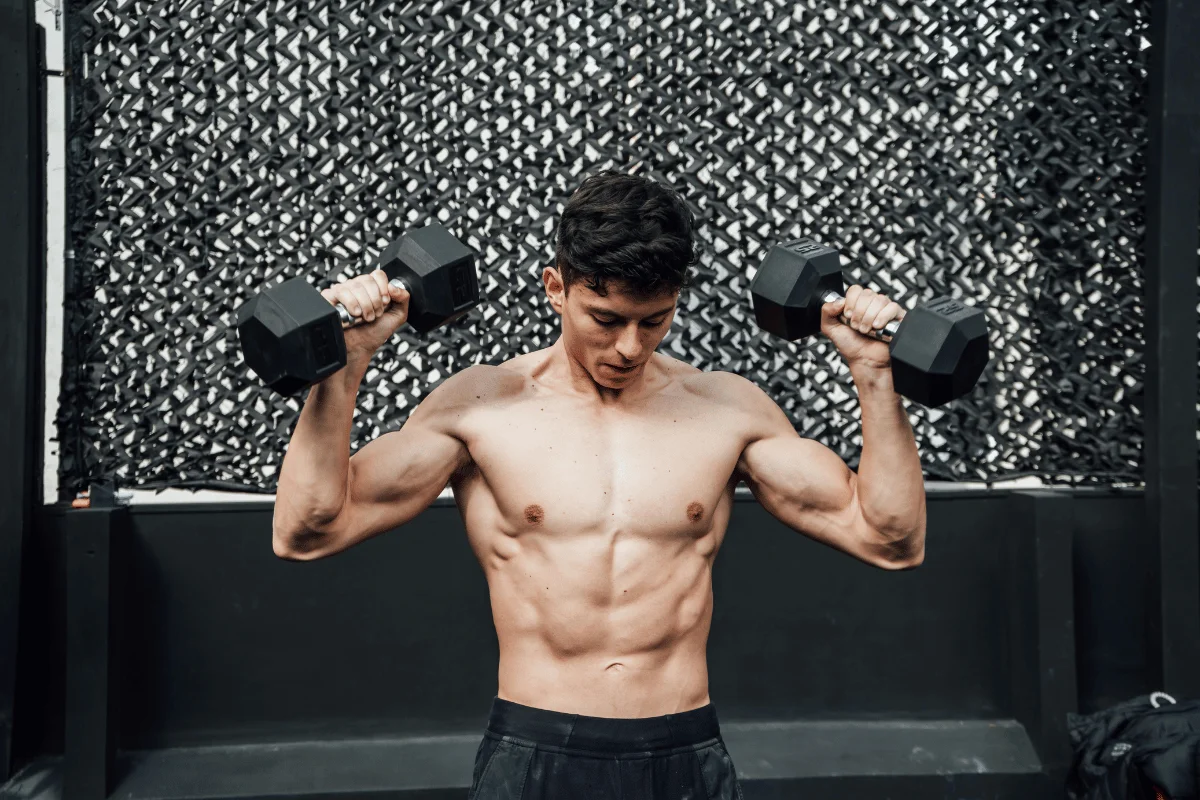 Shirtless man lifting dumbbells during a workout session.