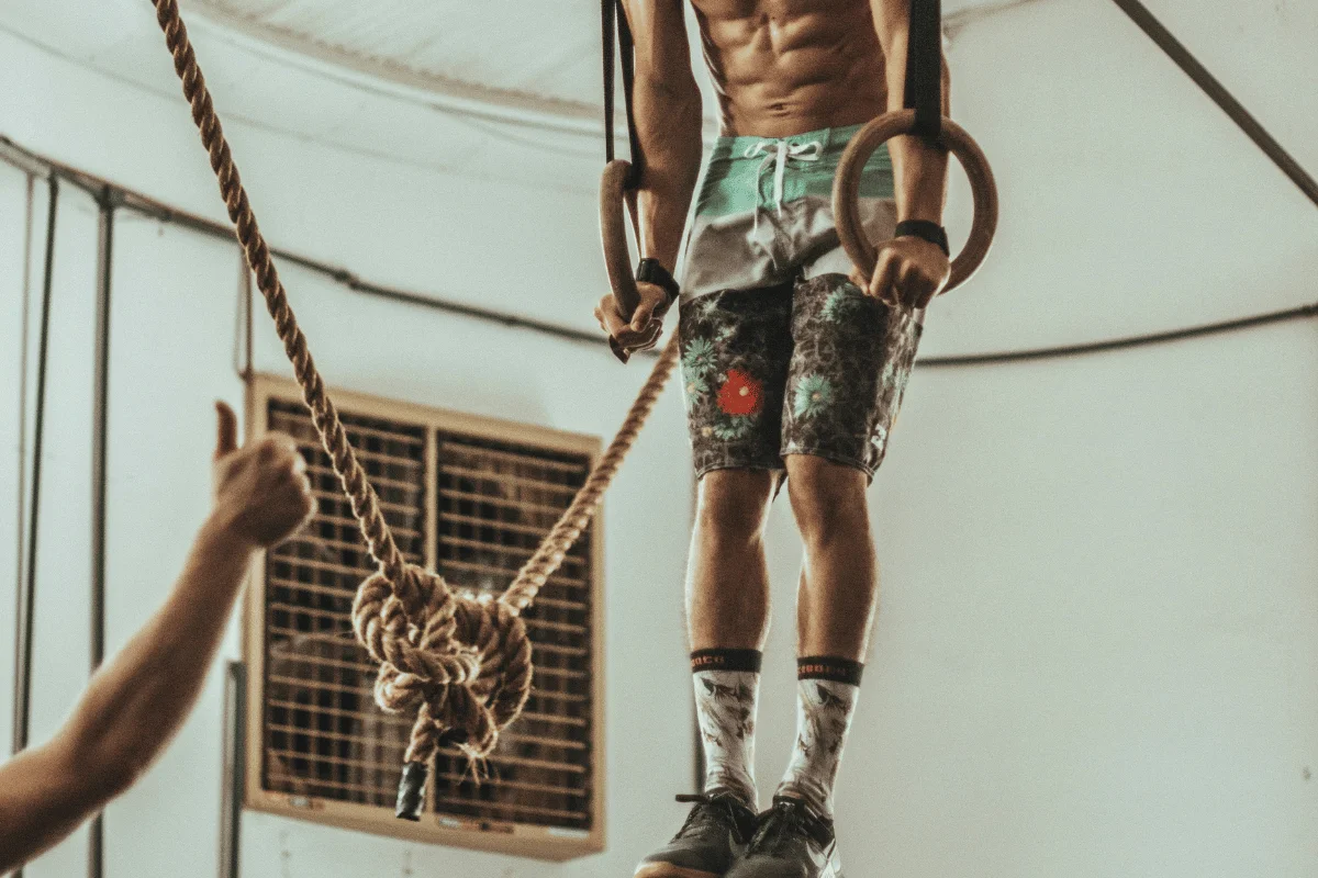 Man performing ring dips in gym, showcasing upper body strength.