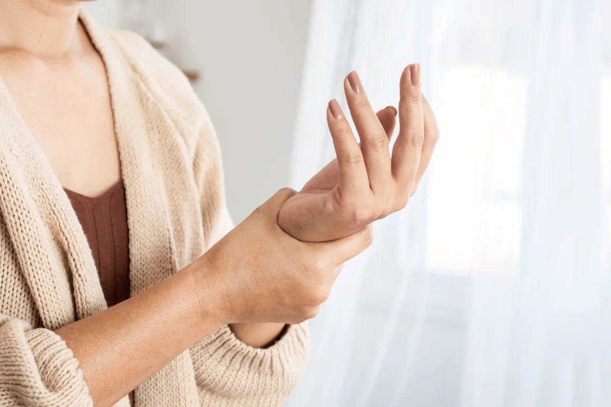 Woman holding her wrist, experiencing joint pain at home.