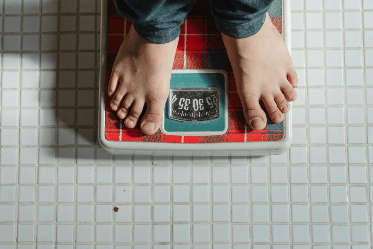 Close-up of feet standing on a vintage bathroom scale with a red checkered pattern.