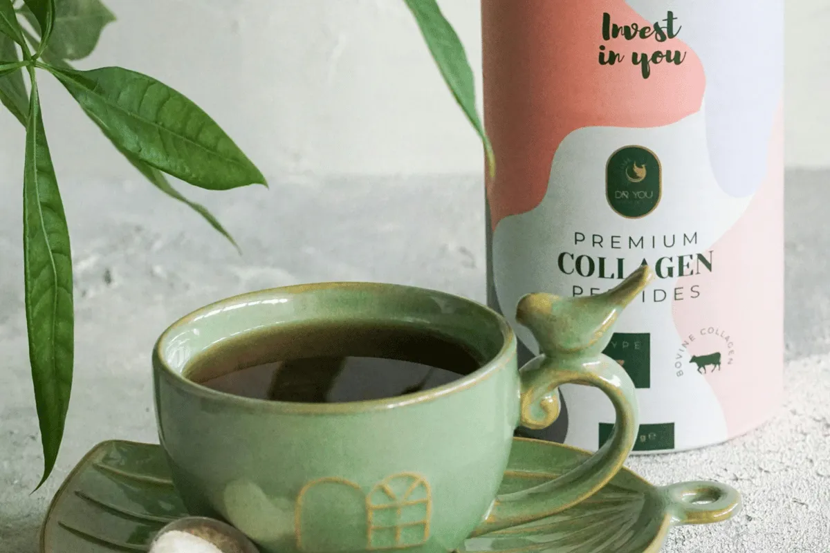 A cup of coffee next to a container of premium collagen peptides with a green leaf in the background.