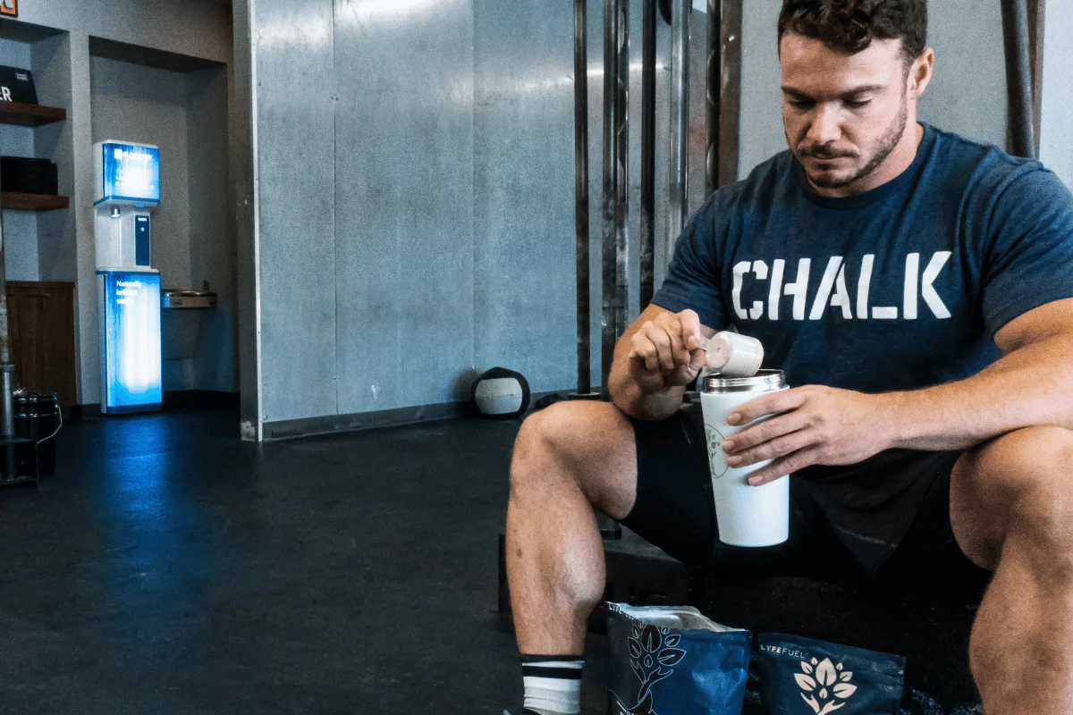 Athlete sitting in the gym mixing a protein shake after an intense workout.