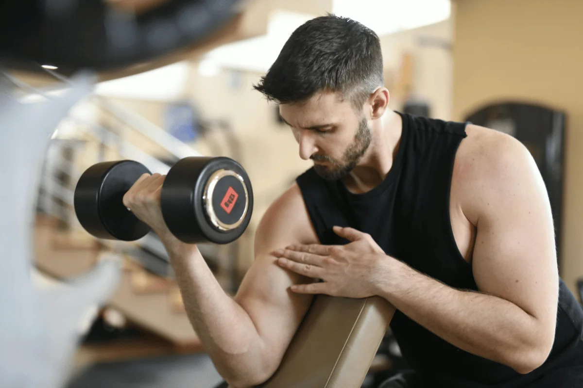 Man performing a bicep curl with a dumbbell at the gym.