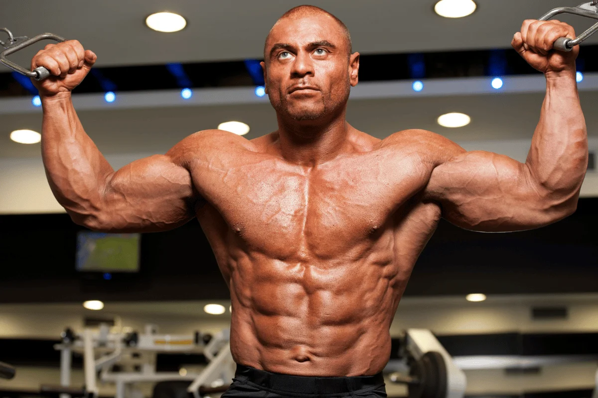 Muscular person flexing biceps in a gym setting.