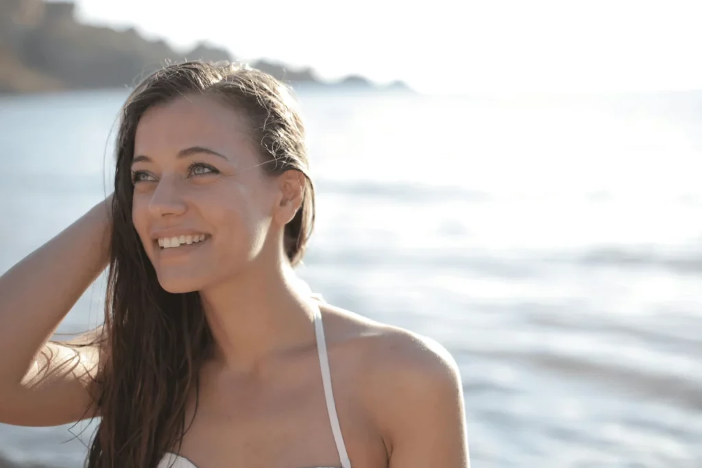 Smiling woman with wet hair enjoying a sunny beach day.