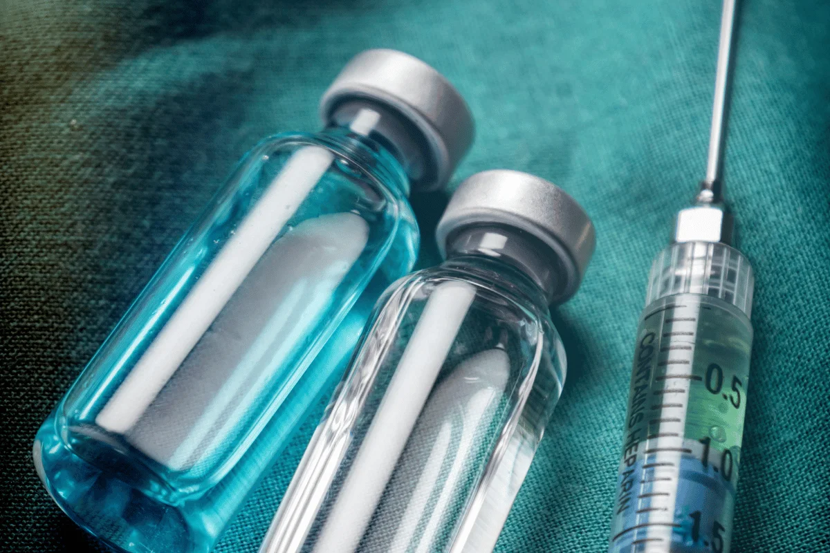 Medical vials containing a blue solution next to a syringe, representing healthcare.