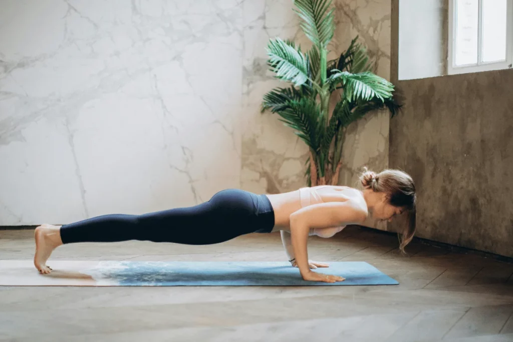 Woman practicing a yoga push-up pose on a mat in a peaceful indoor space.