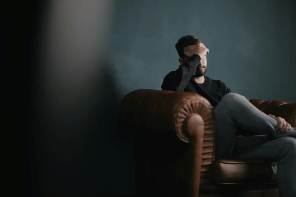 Man sitting on a leather armchair with his hand covering his face.