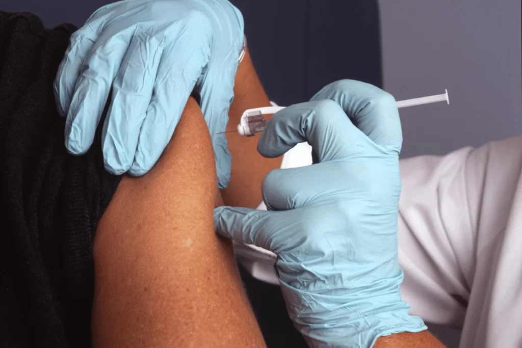 A healthcare professional administering a vaccine injection into a patient's upper arm.