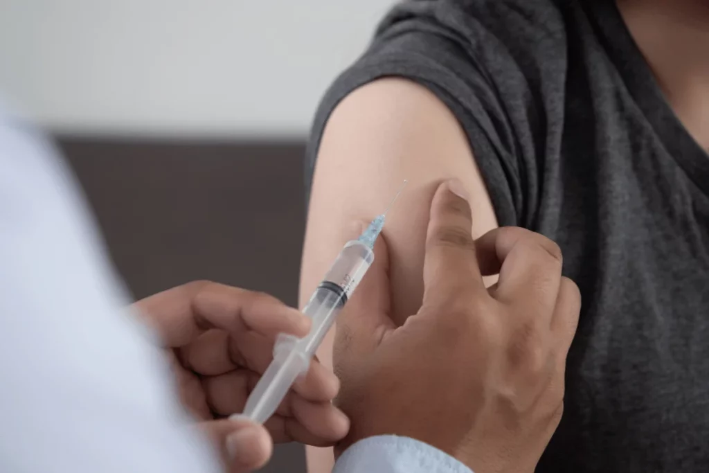 Healthcare professional administering vaccine injection into upper arm.