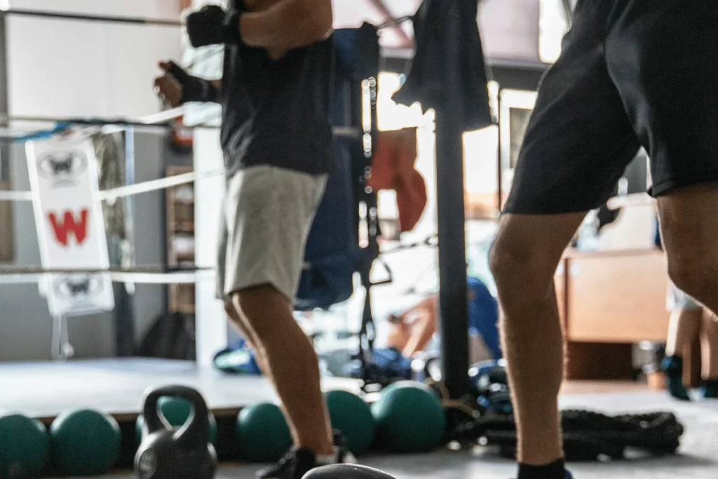 Boxing gym scene with kettlebells and medicine balls in the foreground.