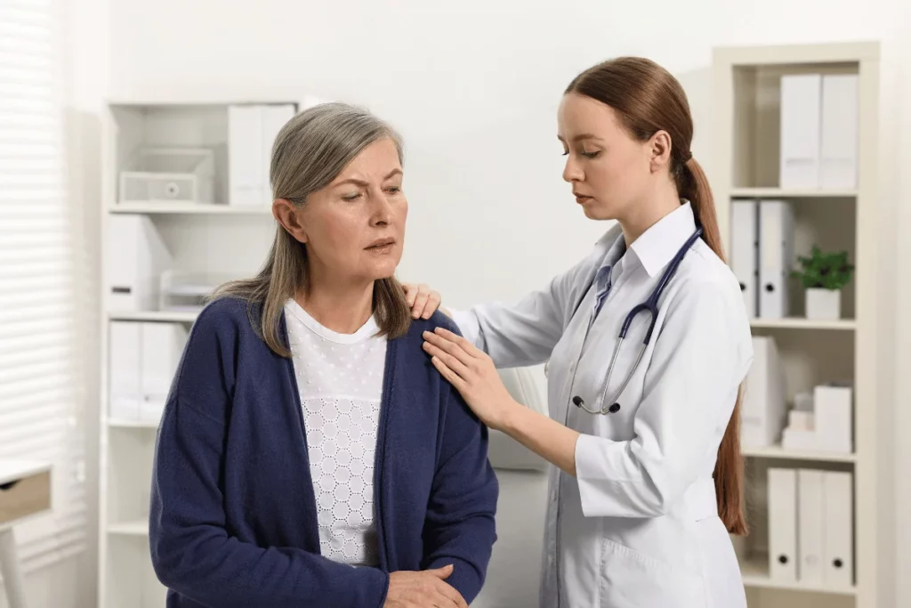 Doctor providing comforting support to an elderly patient in a medical office.