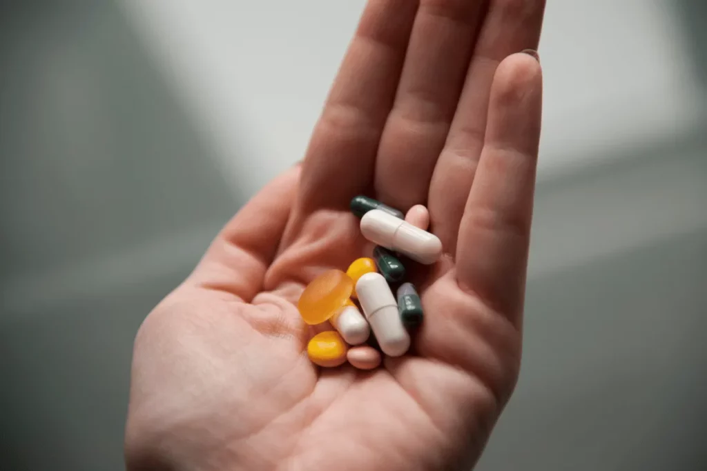 Close-up of a hand holding different types of pills and supplements.