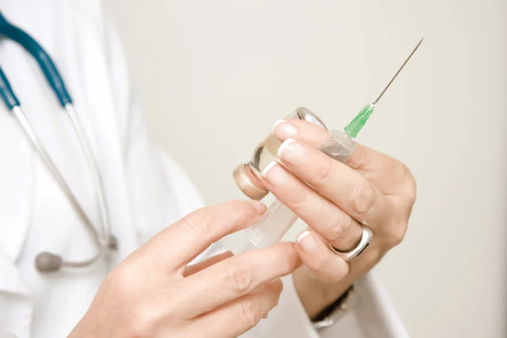 Doctor preparing an injection with a syringe and medication vial.