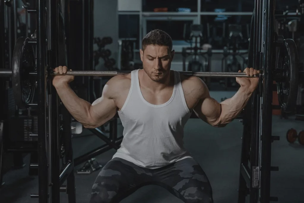 Bodybuilder doing a heavy barbell squat in the gym, targeting leg muscles for strength and power.