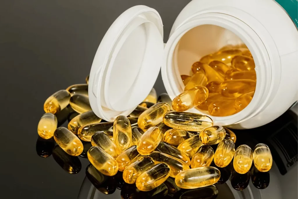 Softgel capsules of dietary supplements spilling from a white bottle.