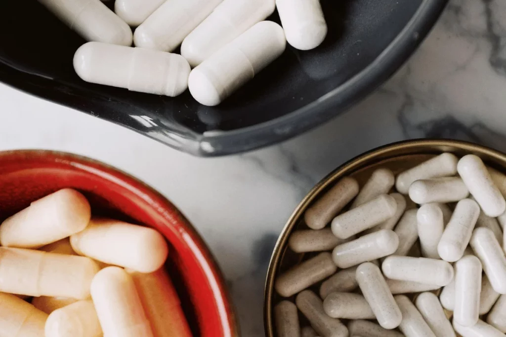 Close-up of assorted supplement capsules in black, red, and gold bowls.