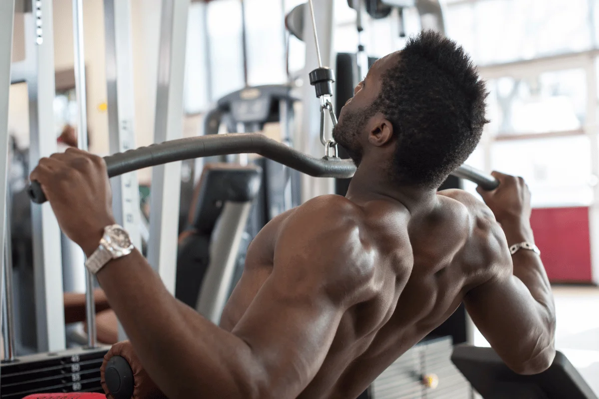 Muscular man performing lat pulldown exercise at the gym.