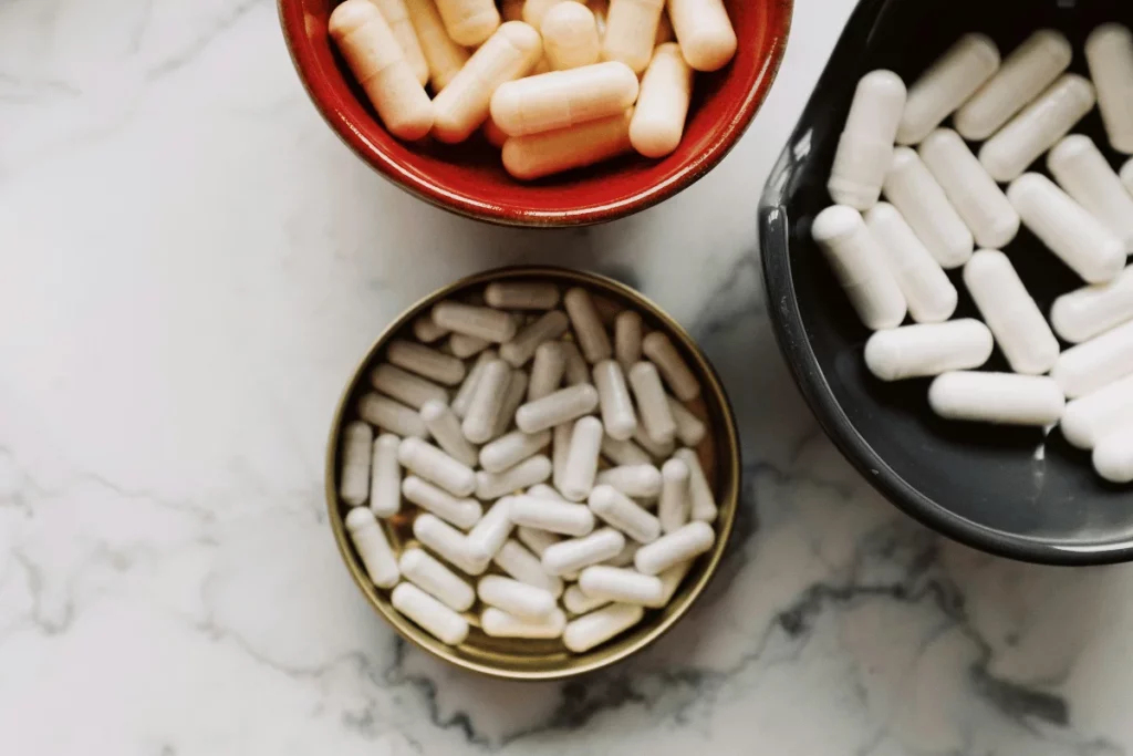 Three bowls filled with different colored capsules on a marble surface.