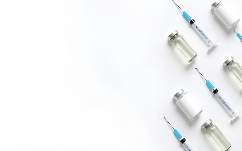Medical syringes and small glass vials arranged diagonally across a white background