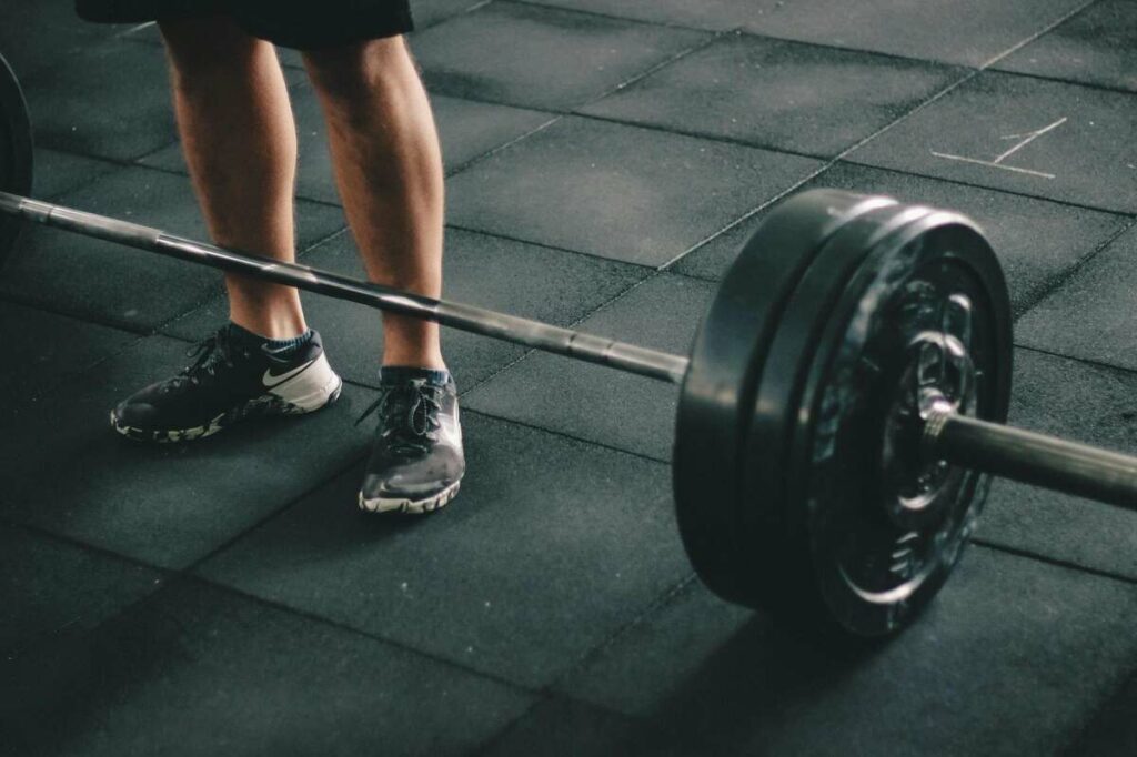 Bodybuilder standing with barbell at his feet