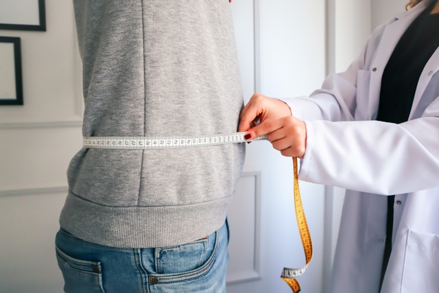 A doctor measuring a woman's waist with a measuring tape